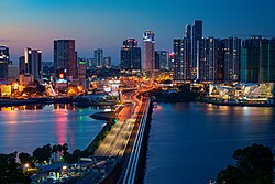 The Johor–Singapore Causeway traversing the Strait of Johor is one of the world's very busiest international border crossings. Johor Bahru is in the background.