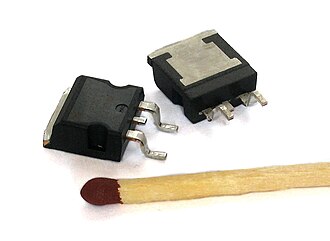 Two power MOSFETs in D2PAK surface-mount packages. Operating as switches, each of these components can sustain a blocking voltage of 120 V in the off state, and can conduct a con­ti­nuous current of 30 A in the on state, dissipating up to about 100 W and controlling a load of over 2000 W. A matchstick is pictured for scale.