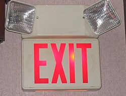 An exit sign in the United States, showing the way to the nearest exit, with two emergency lights in case an electrical failure knocks out room lighting.