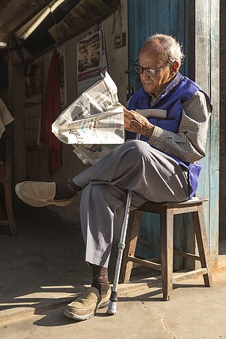 Senior reading a newspaper in Nepal