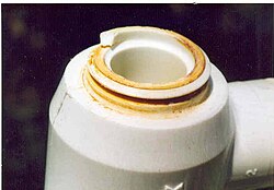 Chlorine "attack" on an acetal resin plumbing joint resulting from a fractured acetal joint in a water supply system which started at an injection moulding defect in the joint and slowly grew until the part failed. The fracture surface shows iron and calcium salts that were deposited in the leaking joint from the water supply before failure and are the indirect result of the chlorine attack.